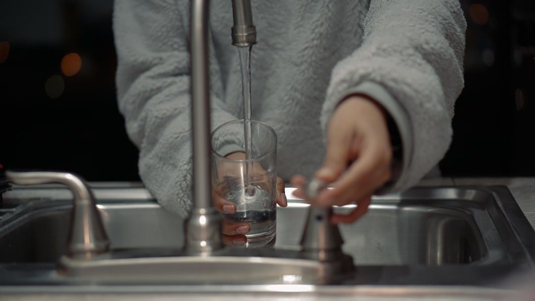Glas fyldes med vand fra en køkkenhane over en stålvask
